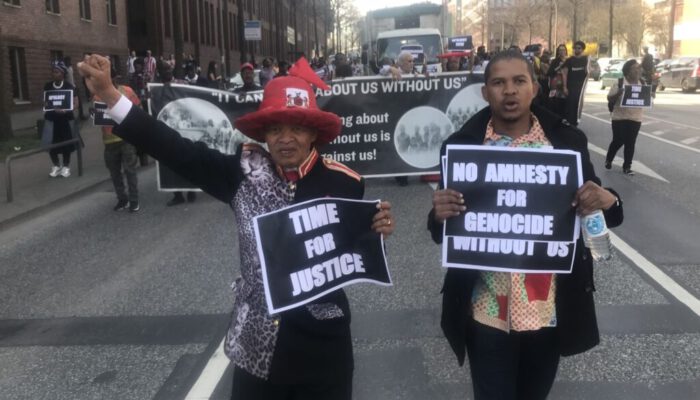 "Time for Justice" und "No Amnesty for Genocide" - NTLA-Chief Kooper und Aktivist Paul Thomas vom „The Landless People's Movement“ (LPM) bringen während der Demonstration am 08. April quer durch die Hamburger Innenstadt ihre Kernforderungen zum Ausdruck...